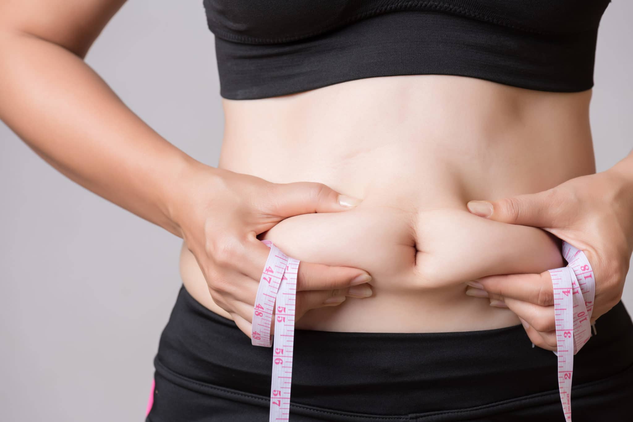 Fat woman hand holding excessive belly fat with measuring tape. Healthcare and woman diet lifestyle concept to reduce belly and shape up healthy stomach muscle.