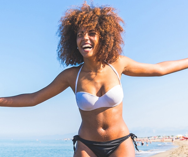 woman smiling at beach after breast reduction surgery